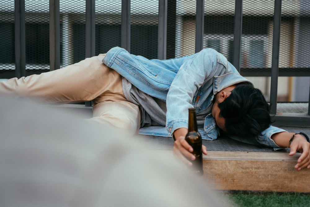 Asian,Sleepy,Drunk,Man,Holding,Beer,Bottle,And,Lying,On