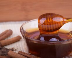 Spoon,With,Honey,And,Cinnamon,Sticks,On,A,Table