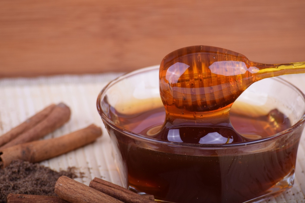 Spoon,With,Honey,And,Cinnamon,Sticks,On,A,Table